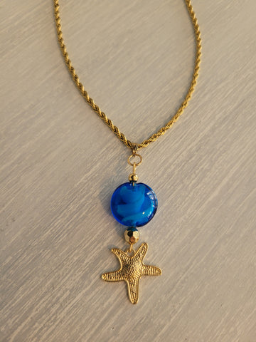 Gold color necklace with glass stone charm and starfish.